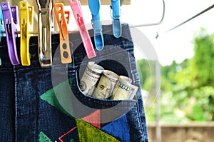 Jeans hanging and dollar bank notes in a pocket.