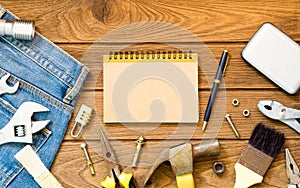 Jeans and many handy tools, blank space notebook on wooden background top view with copy space for text