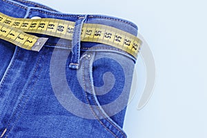 Jeans and measuring tape close-up, concept of healthy lifestyle and losing weight, copy space