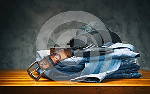 Jeans and shirt with accessories on wooden table.