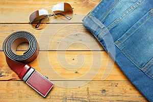 Jeans, sunglasses and leather belt on the wooden vintage