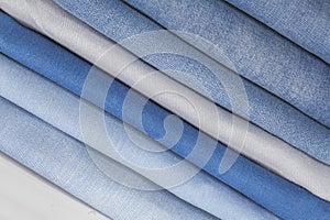 Jeans of various fabrics lie in a pile on a white background, isolate