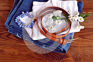 Jeans, white t-shirt, brown belt on wooden background. Women clothes set. Close up