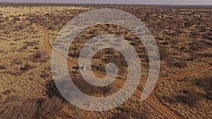 A jeep with an open trunk travels across the savannah of Namibia.