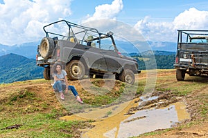 Jeeping car mountain travel. Beautiful girl rest next dirty jeep and big puddle of mudd