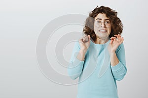 Jeez, take it away from me. Portrait of afraid disgusted young european woman with short curly hair in glasses