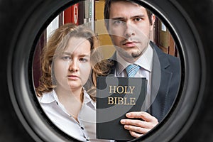 Jehovah witnesses are showing bible behind door. View from peephole photo