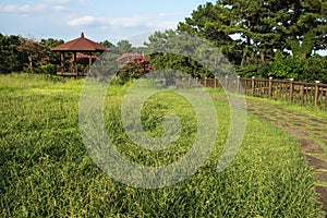 Jeju olle rounded pathway through a park with a little gardenhouse in Seogwipo, Jeju Island, South Korea