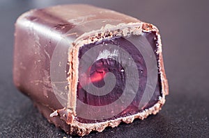 Jelly candy drenched in chopped chocolate. Red, pink dye in gelatin