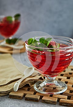 Jelly with strawberries in a glass on a wooden board, against a background of concrete