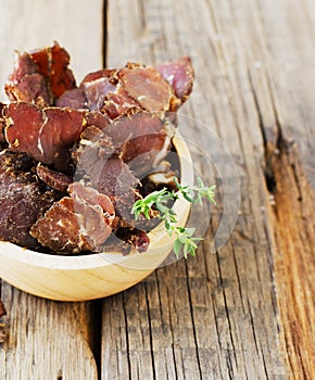 Jerked meat, cow, deer, wild beast or biltong in wooden bowls on a rustic table, selective focus