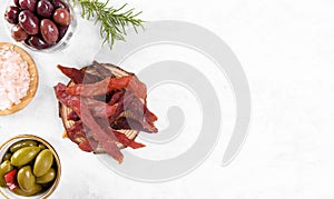 Jerky meat strips with spices, olives, snack for beer on wooden plate