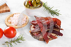 Jerky meat strips with spices, olives, snack for beer on wooden plate