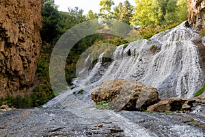 Jermuk waterfall flowing stream picturesque view among the canyon rocks sunlit gorge. Armenian stock photo