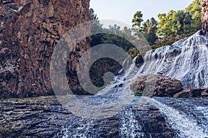 Jermuk waterfall flowing stream picturesque view among the canyon rocks sunlit gorge. Armenian stock photo