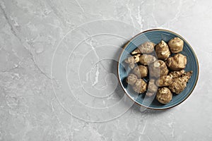 Jerusalem artichokes on light grey marble table, top view. Space for text