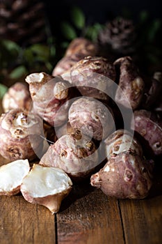 Jerusalem artichokes or topinambour, topinambur, also known as earth apple or sunroot on wooden background.