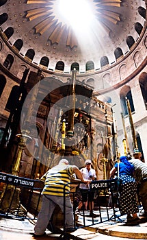 Penetrating sun rays through the rotunda of the dome on aedicula in the Church of the Holy Sepulcher in Jerusalem with visitors