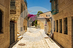 Jerusalem old city empty street alley passage between stone buildings in spring time blossom season clear weather day