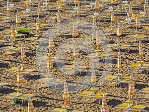 Jesolo, Italy. Beach umbrellas and sun beds at Italian sandy beach. Raws of Yellow and white umbrellas. Aerial view at sunrise