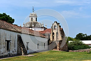 Old colonial builng with adobe and rocks wall, red tile roof. A bell tower and a dome. The Jesuits domains in Argentina. photo