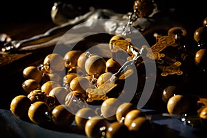 Jesus Christ catholic crucifix and wooden rosary beads under beam of light