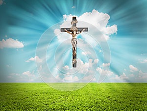 Jesus Christ on cross radiates light in sky over landscape