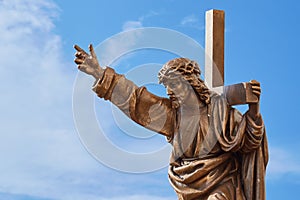 Jesus Christ with cross sculpture at the blue sky