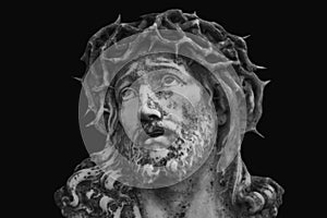 Jesus Christ in a crown of thorns. Fragment of an ancient statue isolated on black background
