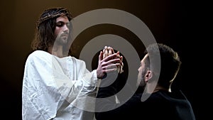 Jesus Christ holding hands of praying man, religious support, sins forgiveness