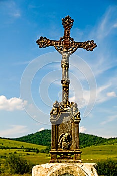 Jesus Christ on old wayside cross in meadow.