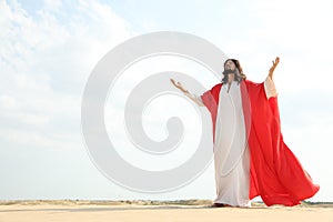 Jesus Christ raising hands in desert. Space for text