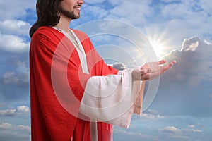 Jesus Christ reaching out his hands and praying against blue sky