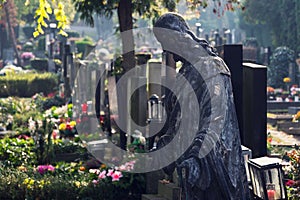 Jesus Christ statue among graves, autumn on cemetery, Prague, Czech Republic, sunny day, All souls day