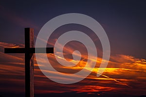 Jesus Christ wooden cross on a background with dramatic, colorful sunset, and orange, purple sky