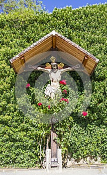 Jesus christ, wooden crucifix, spontaneous religiosity of the people in the midst of plants and roses