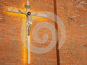 Jesus on a crucifix in front of a stone brick wall