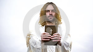 Jesus giving Holy Bible, calling for prayer, righteous living in catholicism