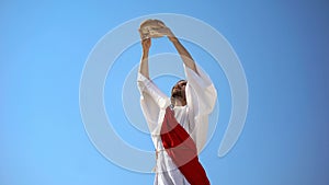 Jesus God raising bread in hands to sky, blessing sacramental food, Eucharist