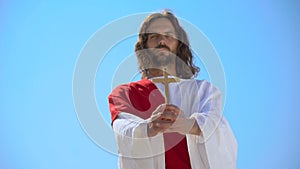 Jesus holding wooden cross against blue sky, conversion to Christianity, baptism