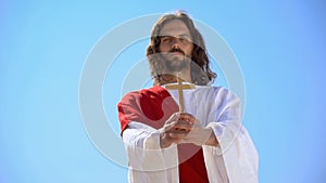 Jesus holding wooden cross against blue sky, conversion to Christianity, baptism