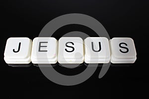 Jesus text word title caption label cover backdrop background. Alphabet letter toy blocks on black reflective background. White al