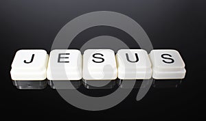 Jesus text word title caption label cover backdrop background. Alphabet letter toy blocks on black reflective background. White al