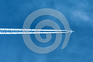 Jet aircraft flying at high altitude with contrails