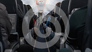 Jet airplane interior view with unrecognizable passengers in comfortable seats of aircraft. Sign Exit.