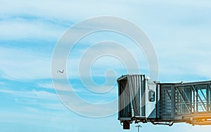 Jet bridge after commercial airline take off at the airport and the plane flying in the blue sky and white clouds. Aircraft