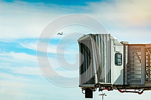 Jet bridge after commercial airline take off at the airport and the plane flying in the blue sky and white clouds. Aircraft