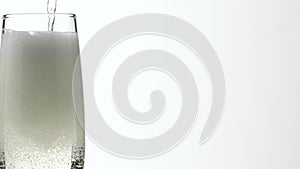 Jet Of Champagne Of Carbonated Drink Or An Alcoholic Cocktail Is Poured Into Glass On A White Background.