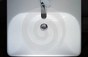 A jet of clean water flows from a faucet into a white sink.