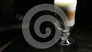A jet of coffee is poured into a glass of mochaccino or latte.Blurred background.Copy space